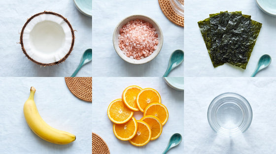A flat lay grid of natural electrolyte foods including coconut, pink salt, dried seaweed, banana, and orange slices.