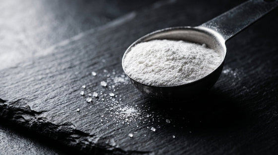 A dramatic macro shot of white creatine powder on dark slate with scattered crystals, illustrating a creatine mythbusting feature.