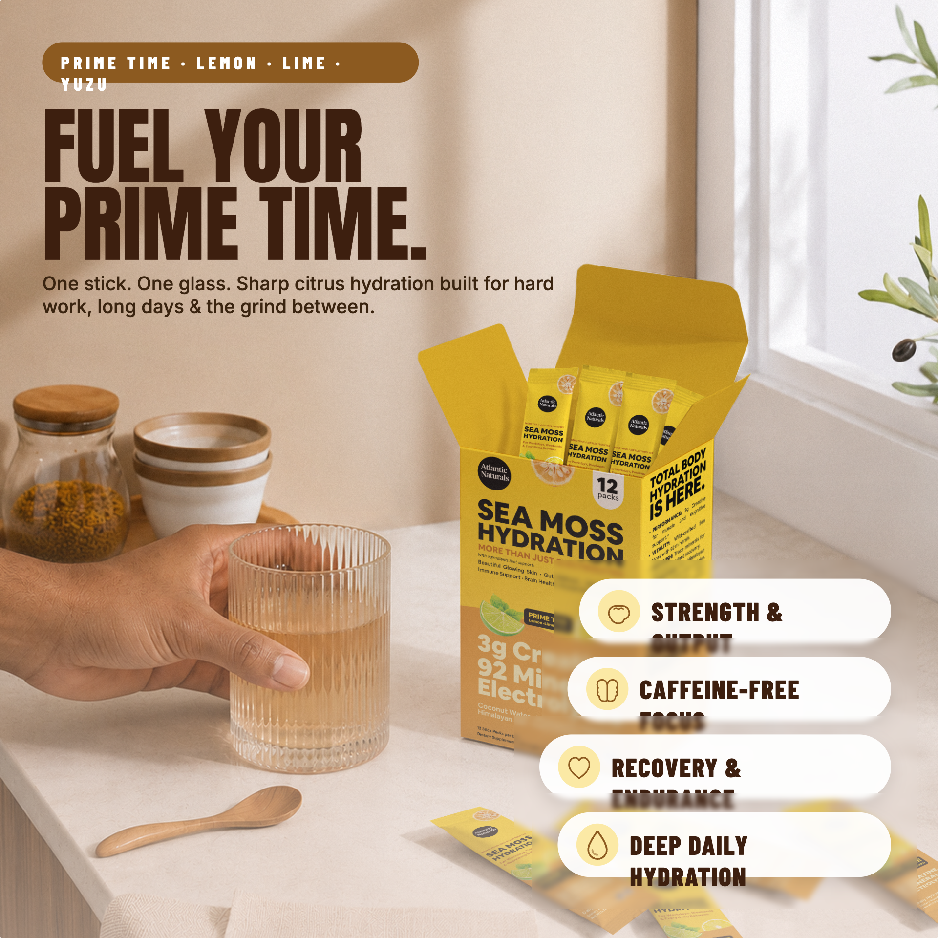 A person holds a glass of prepared drink beside an open box of Sea Moss Hydration sticks on a kitchen counter, with text callouts about strength, focus, recovery, and daily hydration. The product packaging is yellow and black, and the scene includes jars and a spoon as props. prime time